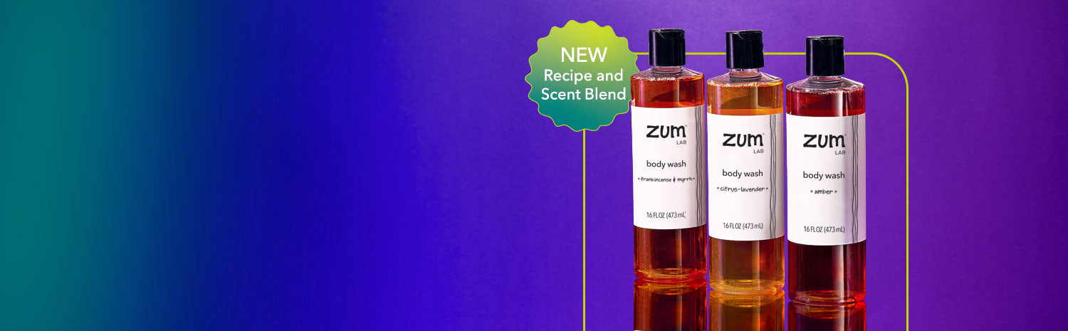 Three bottles of liquid body wash in the scents Frankincense & Myrrh, Citrus-Lavender, and Amber on a mirrored surface with a green, blue, and purple gradient background. Lime green stroked box behind with a badge saying 'NEW Recipe and Scent Blend' beside the bottles.