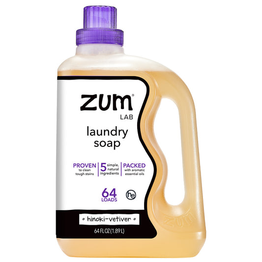 A 64 fl oz bottle of Zum Lab laundry soap with a translucent amber-colored liquid inside, a purple cap, and a white label with black and purple text.