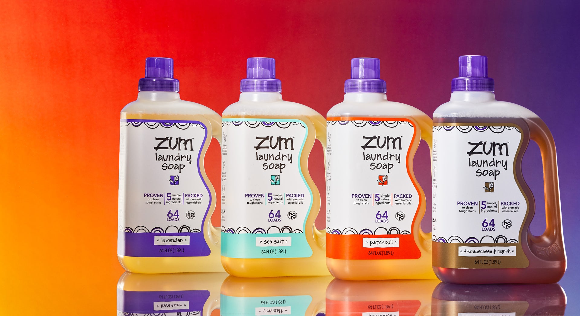 Lavender, Sea Salt, Patchouli, and Frankincense & Myrrh 64 fl. oz. bottles of laundry soap lined up diagonally on a mirrored surface. Orange to purple gradient background.