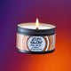 A lit amber scented soy candle flying in the air with a purple to orange gradient background.