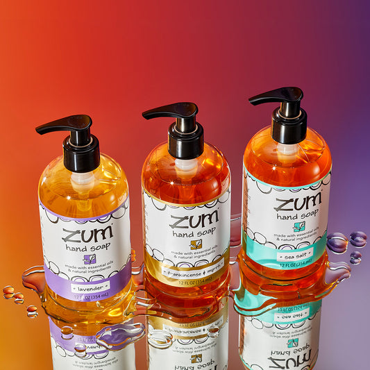 Lavender, Frankincense & Myrrh, and Sea Salt scented bottled hand soaps on a mirrored watery surface. 