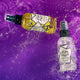 Lemongrass and Lavender room & body spray bottles splashing on a purple watered surface.