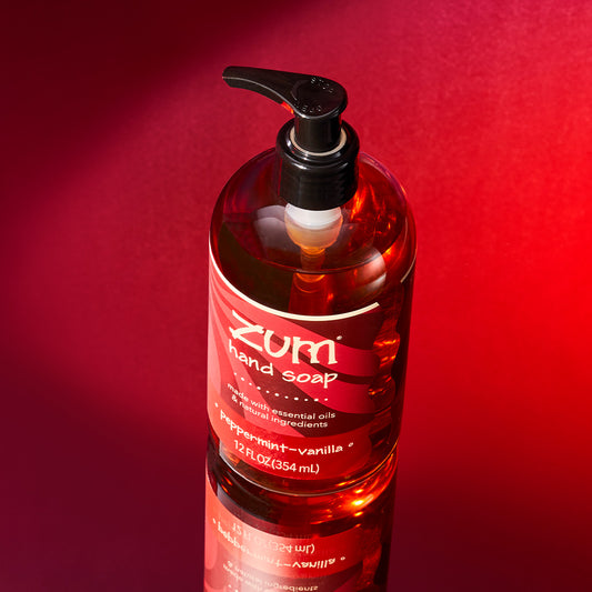Peppermint-Vanilla scented hand soap bottle with a pump sitting on a mirrored surface with a red gradient background.