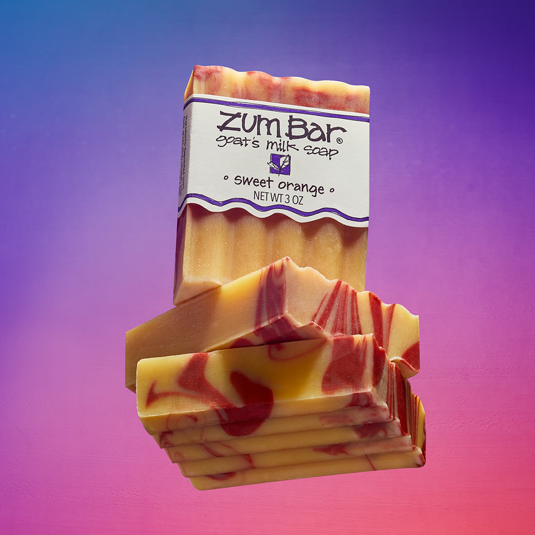 A stack of unlabeled Sweet Orange bar soaps with a labeled on on top. Blue, purple, and orange gradient background.