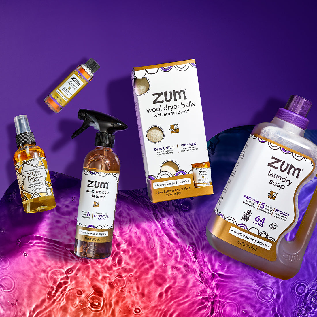 Top down shot of Frankincense & Myrrh scented products half on a purple wave and half on pink to purple gradient water. From left to right: Mist, All-Purpose Cleaner refill, All-Purpose Cleaner, Wool Dryer Ball Kit, 64 fl oz Laundry Soap.