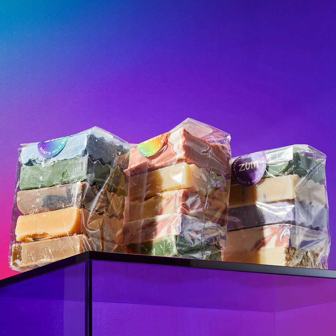 Top Seller, Citrus, and Lavender scented Pound Bags on a purple acrylic box with a blue, orange, and purple gradient background.