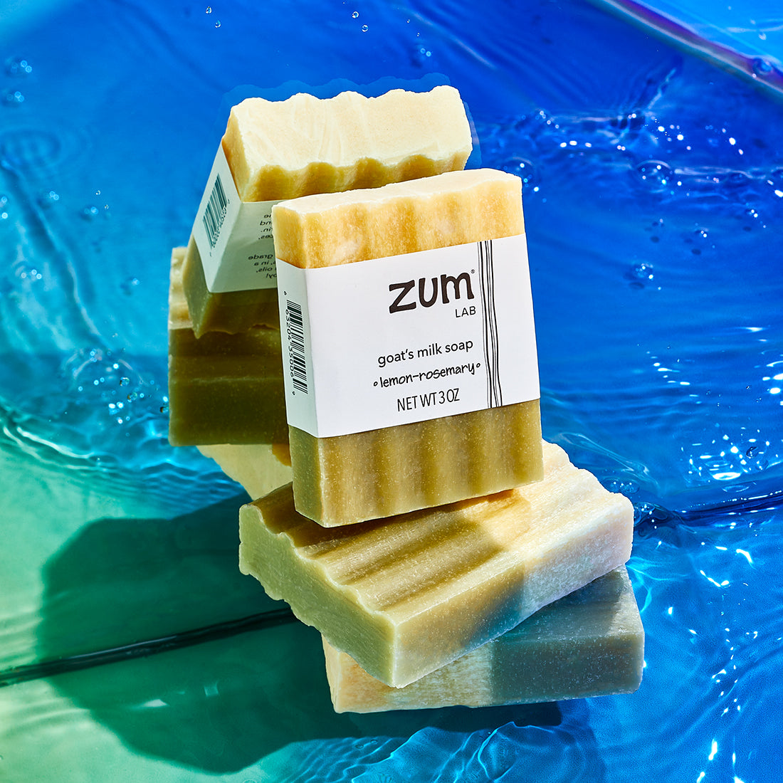 Two stacked Lemon-Rosemary bars, with a labeled version on top leaning agains a mirror. Water at the bottom, with a green to blue gradient colored background.