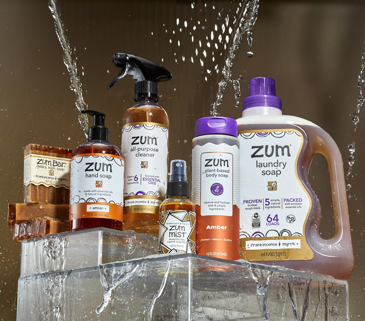 Collection of Zum cleaning products with water splashes on a reflective surface.