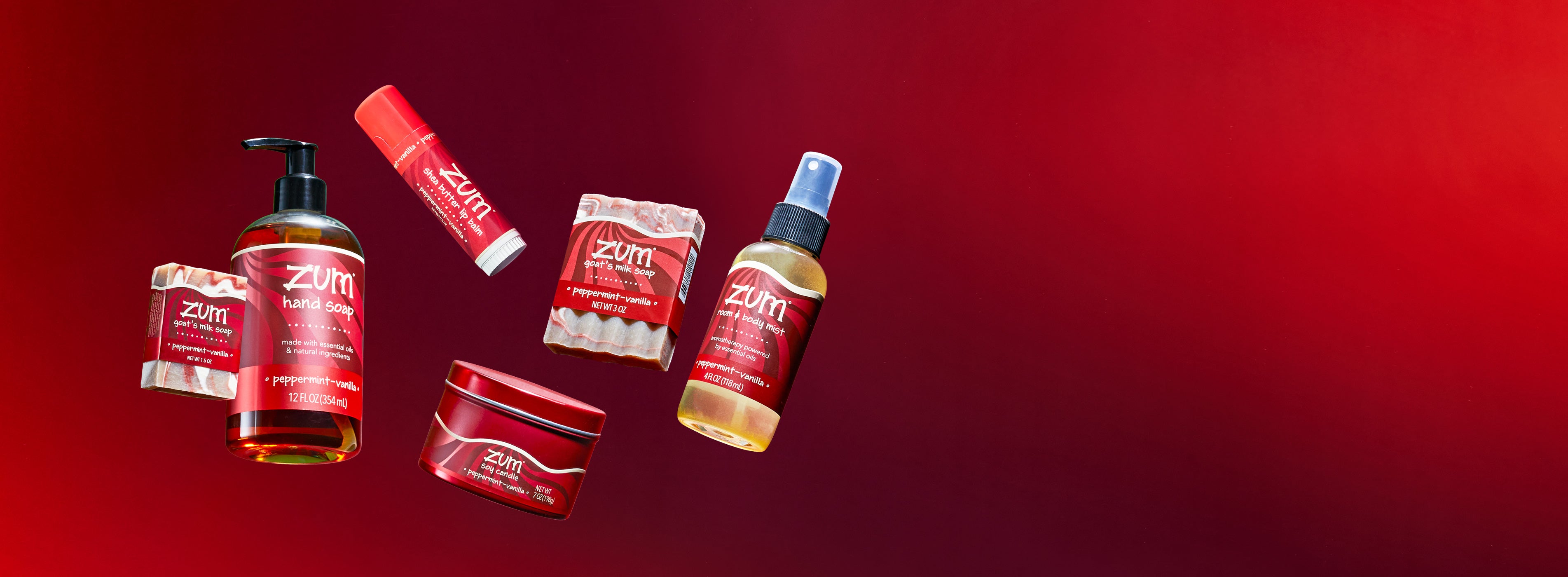 Peppermint-Vanilla scented mini bar soap, hand soap bottle, Zumbo lip balm, soy candle in a tin, bar soap, and mist bottle  flying in the air on a red gradient background.