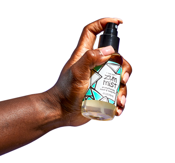 Hand coming from the left spraying a Sea Salt Zum Mist bottle.