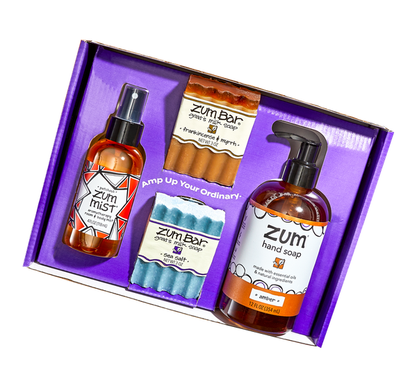 Top down shot of a purple box with an insert with the words "Amp Up Your Ordinary" on it. The You Pick 4 gift set contains four products–Patchouli Zum Mist, Frankincense & Myrrh and Sea Salt Bar Soaps, and an Amber Hand Soap.