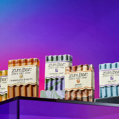 Four soap bars with 'zum Bar' branding on a purple background