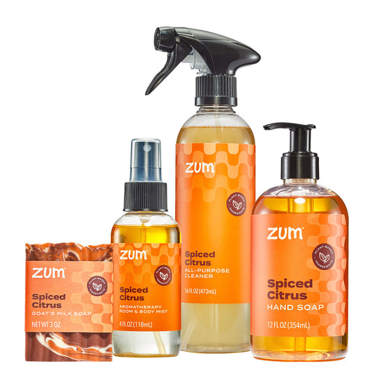 A set of Zum Spiced Citrus body and hand care products on a white background, including a hand soap bottle, a body wash bottle, an all-purpose cleaner spray bottle, and a soap bar.