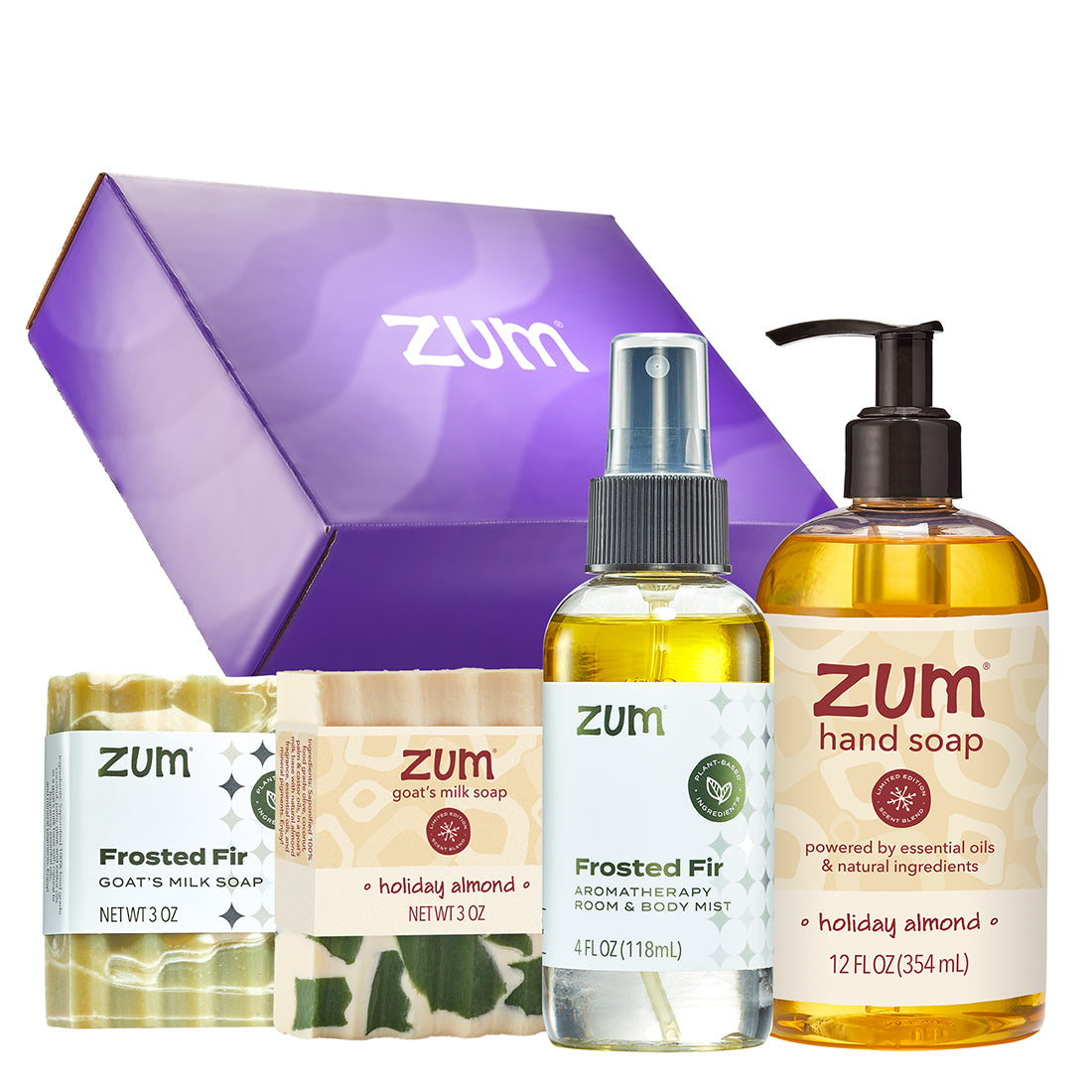 A Zum gift set featuring a purple gift box, a frosted fir goat milk soap bar, a holiday almond aromatherapy room and body mist, and a hand soap bottle, all arranged on a white background.