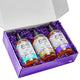 Rectangular gift box with a lid containing 3 hand soaps  with purple crinkle packing material.