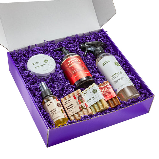 Zum holiday products including Frosted Fir, Peppermint-Vanilla, and Vanilla Spice in a purple gift box with purple crinkle paper.
