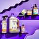 Sweet Orange All-Purpose Cleaner, Frankincense & Myrrh 64 oz Laundry Soap and Zum Bar, Lavender-Mint Zum Bar, Sea Salt Hand Soap, and Amber Mist on two purple shelves.