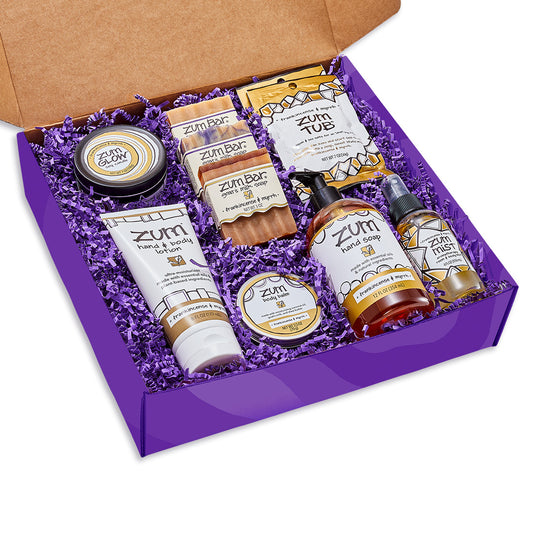 Large purple gift box with purple crinkle inside containing an array of Frankincense & Myrrh scented Zum products.