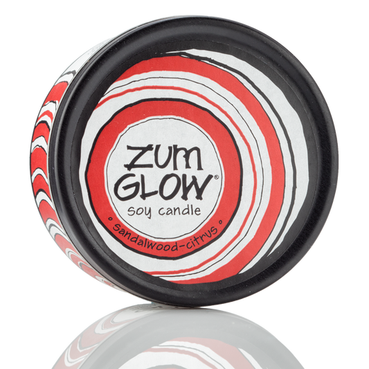 Top view 7 oz Sandalwood-Citrus Candle in a black tin with red and white label that has circular designs.